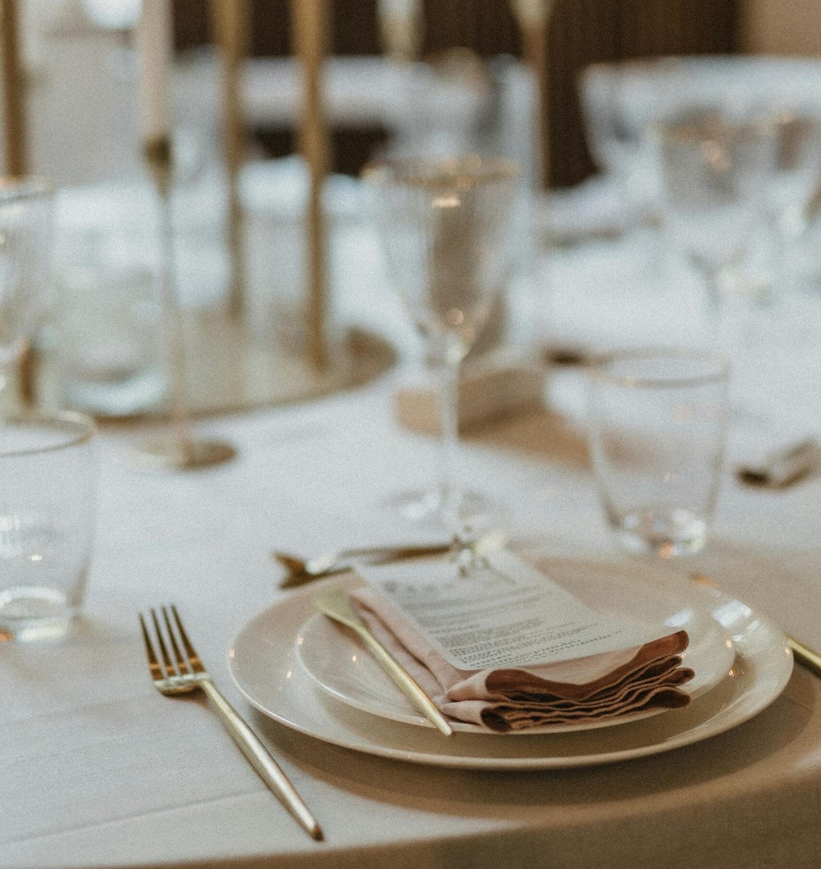 Elegant table setting with candles, glassware, and cutlery for a sophisticated event.
